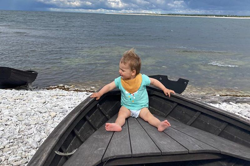 Ein Kleinkind sitzt in einem hölzernen Boot.