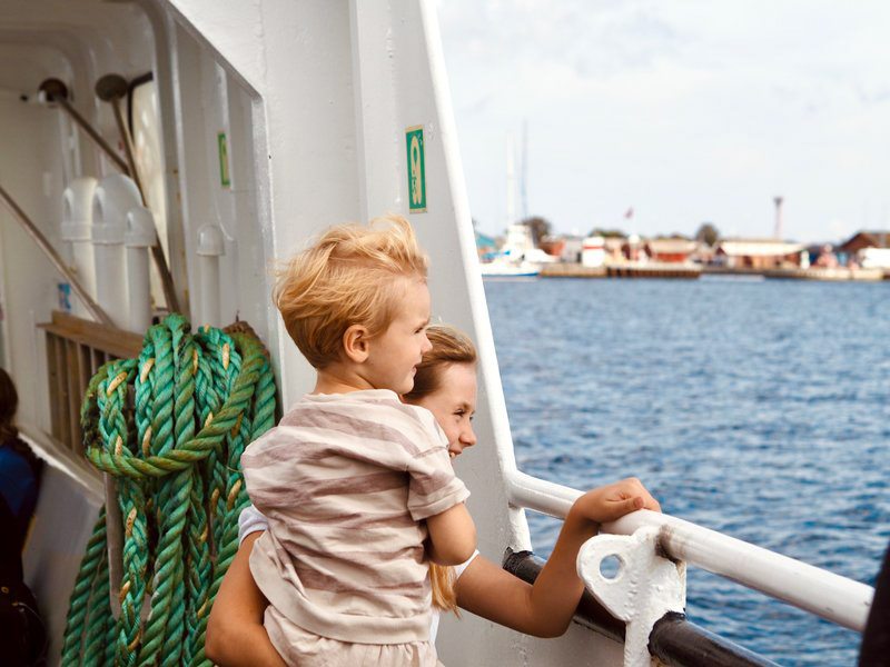 zwei Kinder stehen an der Reling und schauen aufs Wasser