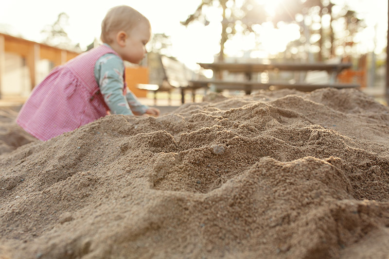 Ein kleines Baby im Sandkasten.