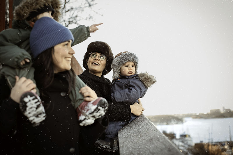 Eine Familie in dicker Winterkleidung steht an einer Holzbarriere. Eines der Kinder zeigt in die Ferne.
